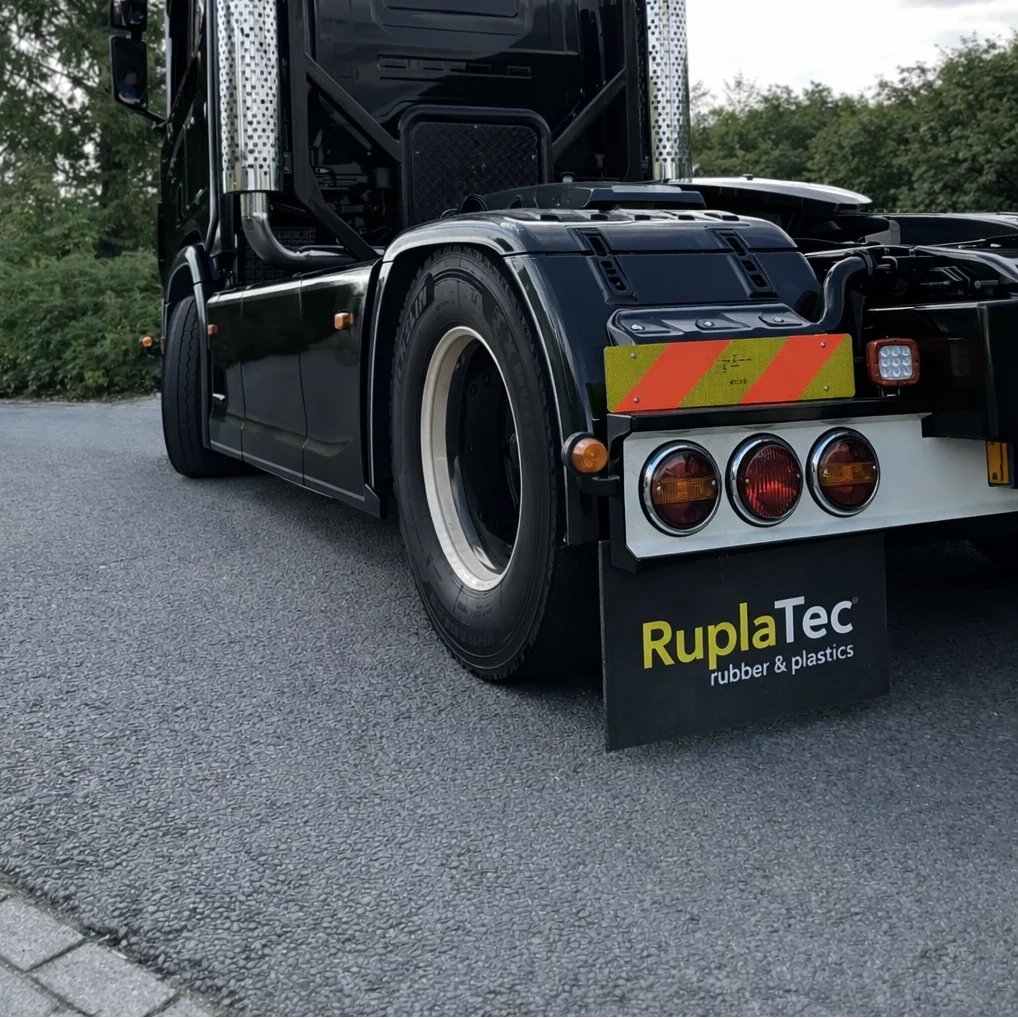 Gepersonaliseerde spatlap op maat met RuplaTec-logo gemonteerd onder een vrachtwagen